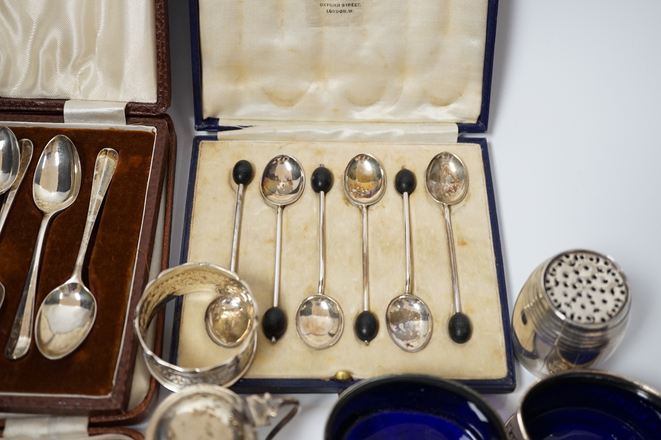 A white metal pepperette modelled as barrel and other silver and plated items including a Georgian caddy spoon, condiments, three cased sets of silver spoons, etc.